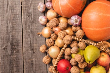 Top view for healthy, natural autumn harvest. On the old boards are pumpkin, nuts, fruits, garlic and onions. Free space for lettering. Flat-lying