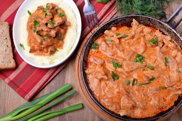Pieces of meat stewed in tomato and sour cream sauce in the frying pan
