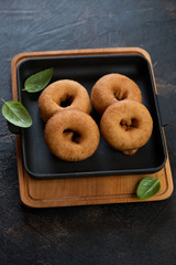 Freshly cooked donuts in a cast-iron serving pan, studio shot over dark brown stone background