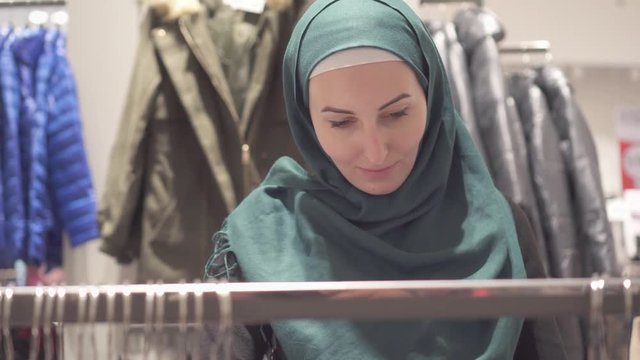 Pretty muslim woman in hijab and with a backpack on shopping in the store,close up