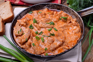 Obraz na płótnie Canvas Pieces of meat stewed in tomato and sour cream sauce in the frying pan