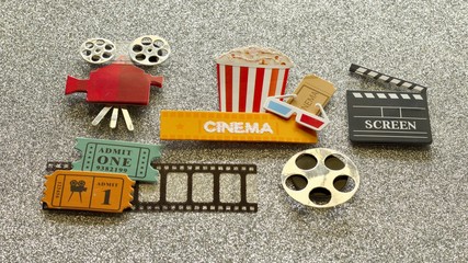 tub of popcorn with cinema sign and 3d glasses movie tickets on film strip projector film reel and open screen box on shiny silver background