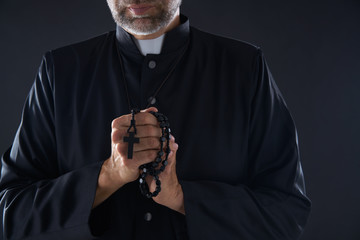 Priest praying hands with rosary beads