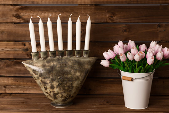 Tulipanes y candelabro de cer&aacute;mica sobre fondo de madera.