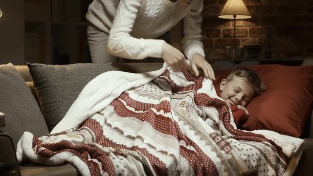 Caring mother tucking her son on Christmas eve