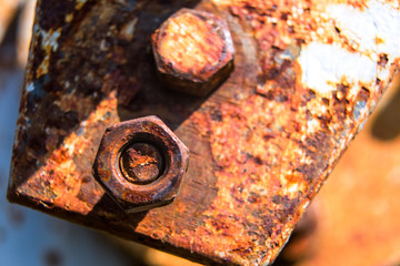 Rusty bolt and nut on a metal plate with corrosion