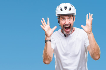 Middle age senior hoary cyclist man wearing bike safety helment isolated background celebrating...