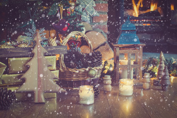 Beautiful Christmas setting, decorated lit up Christmas tree with baubles and ornaments, fireplace with woodburner, lantern, stars and garlands, created snow, toned, selective focus