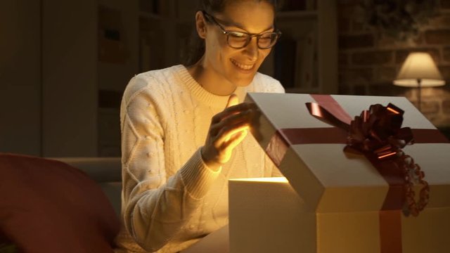 Young happy woman opening a beautiful Christmas gift