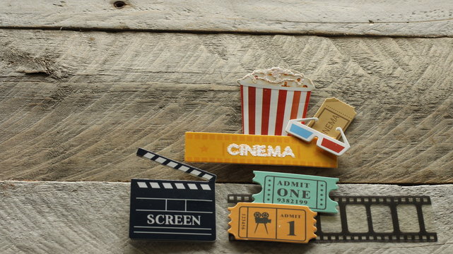 tub of popcorn with cinema sign and 3d glasses movie tickets on film strip and of screen box on wood background with copy space - Powered by Adobe