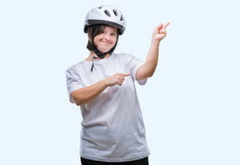 Young adult cyclist woman with down syndrome wearing safety helmet over isolated background smiling and looking at the camera pointing with two hands and fingers to the side.
