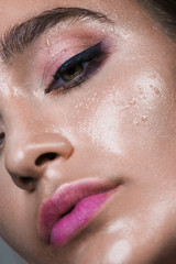 Fototapeta premium Close up gamour beauty woman portrait. Fashion wet shiny skin, with drops sexy gloss lips make-up and pink eyebrows