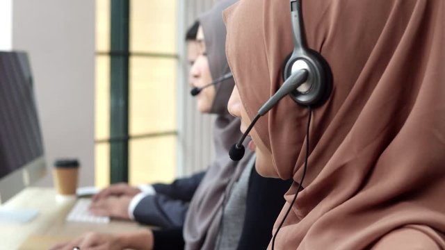 Muslim woman customer service operator team talking on headphone working in call center