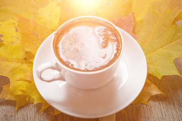 Autumn leaves and coffee cup over wood background with copy space