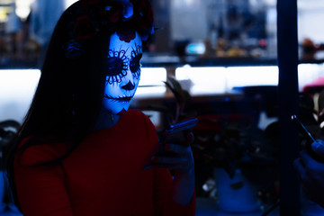Santa Muerte.girl in the dark with make-up halloween, her face lit by cold light from the phone