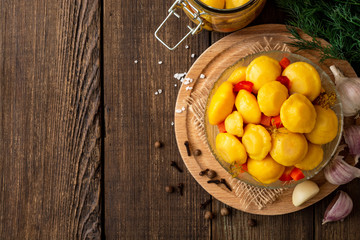 Marinated pattypan squash in glass bowl on dark rustic wooden background. Top view. Copy space.
