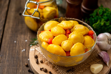 Marinated pattypan squash in glass bowl on dark rustic wooden background. Selective focus.