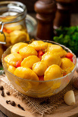 Marinated pattypan squash in glass bowl on dark rustic wooden background. Selective focus.