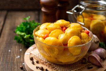Marinated pattypan squash in glass bowl on dark rustic wooden background. Selective focus.