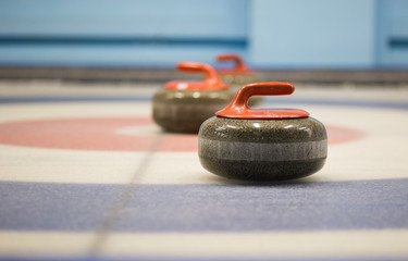 two granite curling rocks on the ice