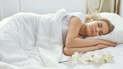 Fototapeta na wymiar Beautiful girl sleeps in the bedroom, lying on bed