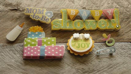 baby shower written on triangular banner with presents mom to be bundle of joy written on cute buttons on a wood background