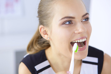 Smiling young woman with healthy teeth brushing her teeth