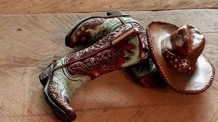 pair of western cowboy boots and cowboy hat laying on a wood background
