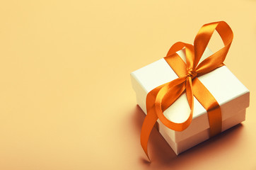 White gift box with orange bright ribbon on yellow background. Beautiful gift for the new year,...