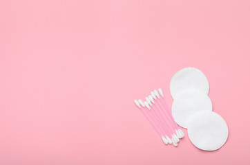Cotton buds and cotton pads on a pink background. Hygiene supplies, beauty tools. Top view, copy space, flat lay