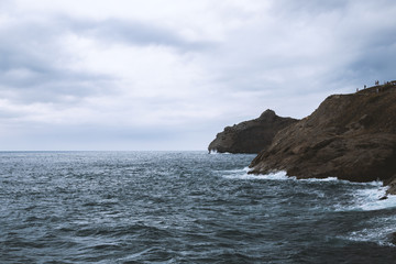 Sea water at mountain coast under cloudy sky