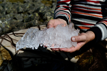 Beautiful piece of  crystalline ice in man's hands on the top of Konzhakovskiy Kamen mountain in summer