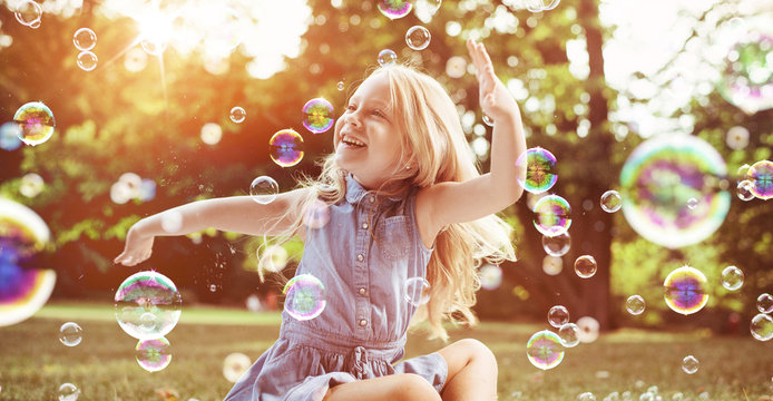 Little blond girl among lots of flying bubbles