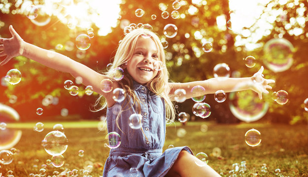 Cute little girl playing soap bubbles