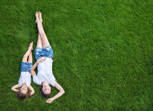 Conceptual portrait of a mother relaxing with daughter on a fresh, green lawn