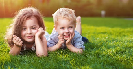 Poster Im Rahmen Fröhliche Geschwister beim Entspannen auf frischem Rasen © konradbak