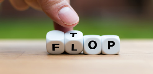 Hand is turning dice and changes the word Flop to Top - obrazy, fototapety, plakaty