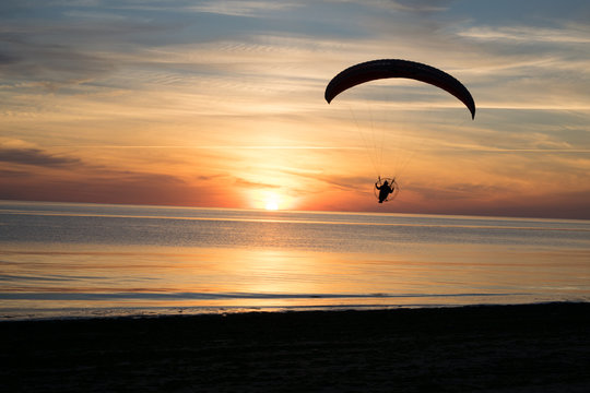 Paraglider over the sea at sunset.
