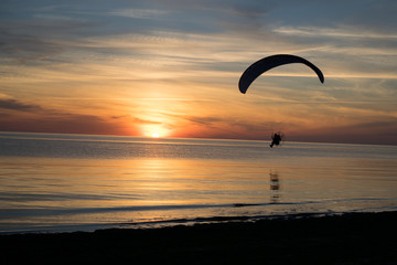 Paraglider over the sea at sunset.