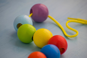 Developmental children's toy. Colored wooden balls on a rope. Colorful wooden baby beads for necklace.