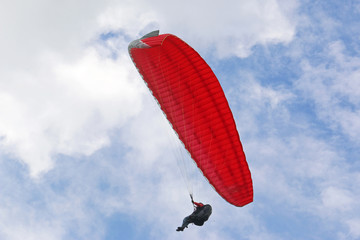 Paraglider flying red wing