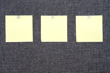 Three Note papers on grey fabric peg board held in place with clear tacks. Copy space on paper note...