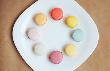 multi-colored macaroons on a white plate craft background