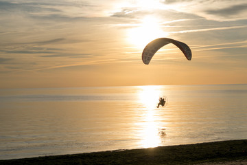 Paraglider over the sea at sunset.