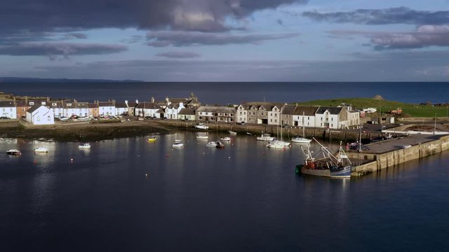 A view of the small Scottish village of Isle of Whithorn in Dumfries and Galloway with small boats anchored in the harbour.