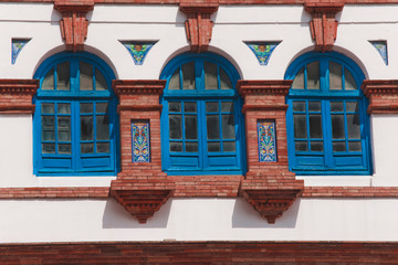 Fototapeta na wymiar Three windows closed blue surrounded by white wall, and bricks 