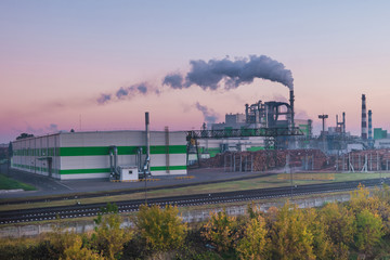 Naklejka na ściany i meble pipes of woodworking enterprise plant sawmill in the morning dawn. Air pollution concept. Industrial landscape environmental pollution waste of thermal power plant
