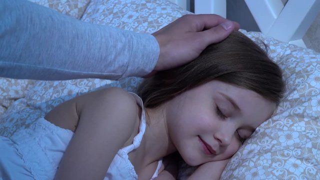 Man strokes his daughter's head, she sleeps. Close up