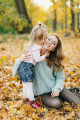 young mother with daughter are walking in the park in the golden autumn