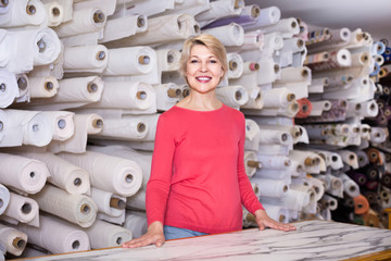 Female shop assistant demonstrating assortment at textile shop